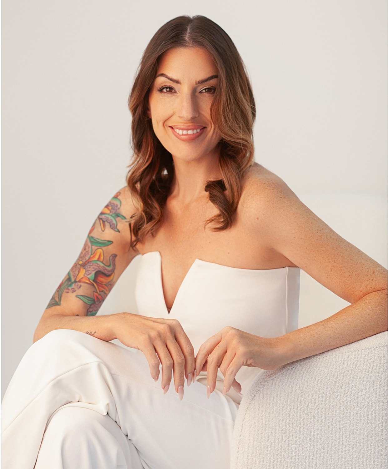 Woman with tattoo in elegant white outfit.