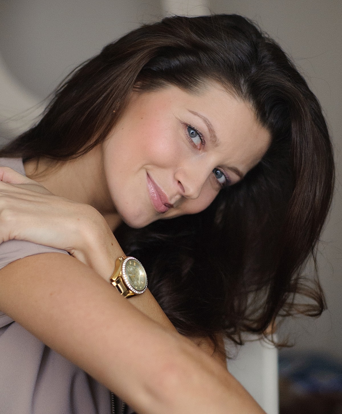 Woman smiling with long dark hair and watch.