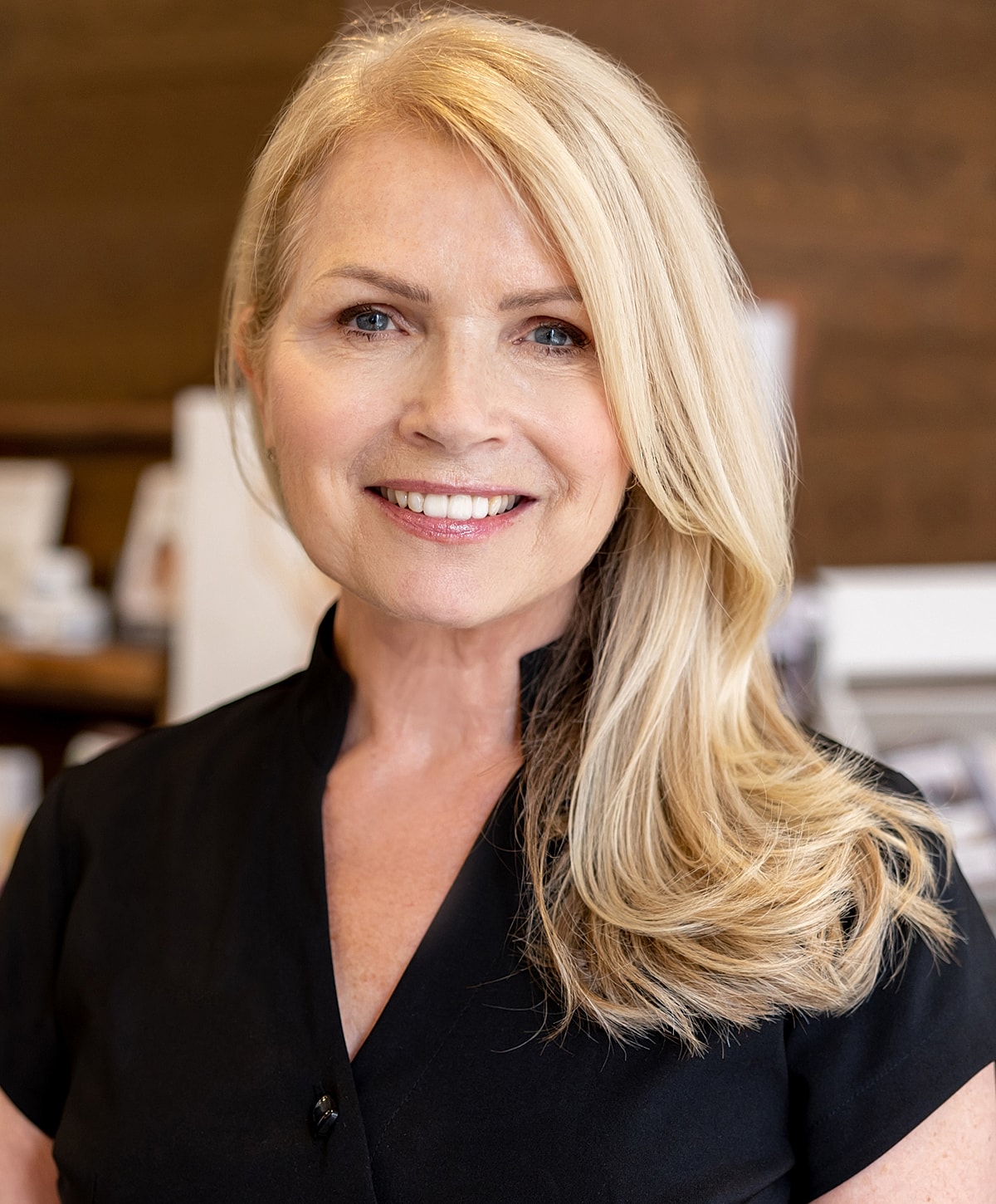 Smiling woman with long blonde hair, black attire.