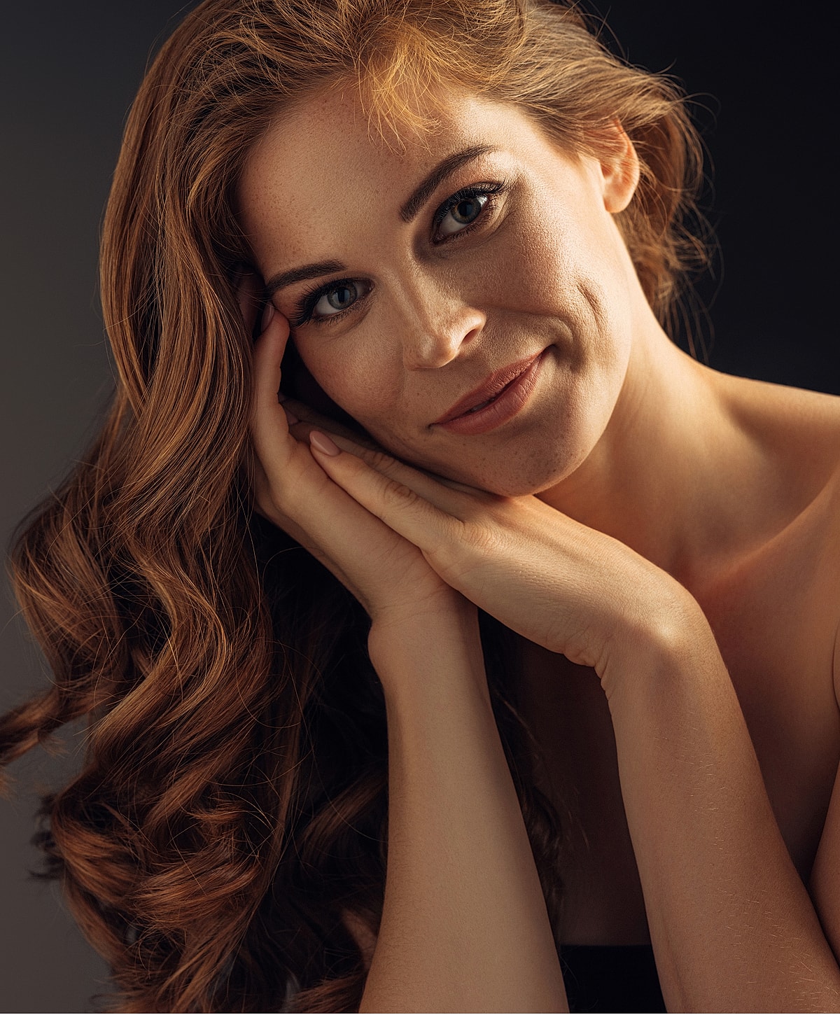 Smiling woman with long, wavy, red hair.