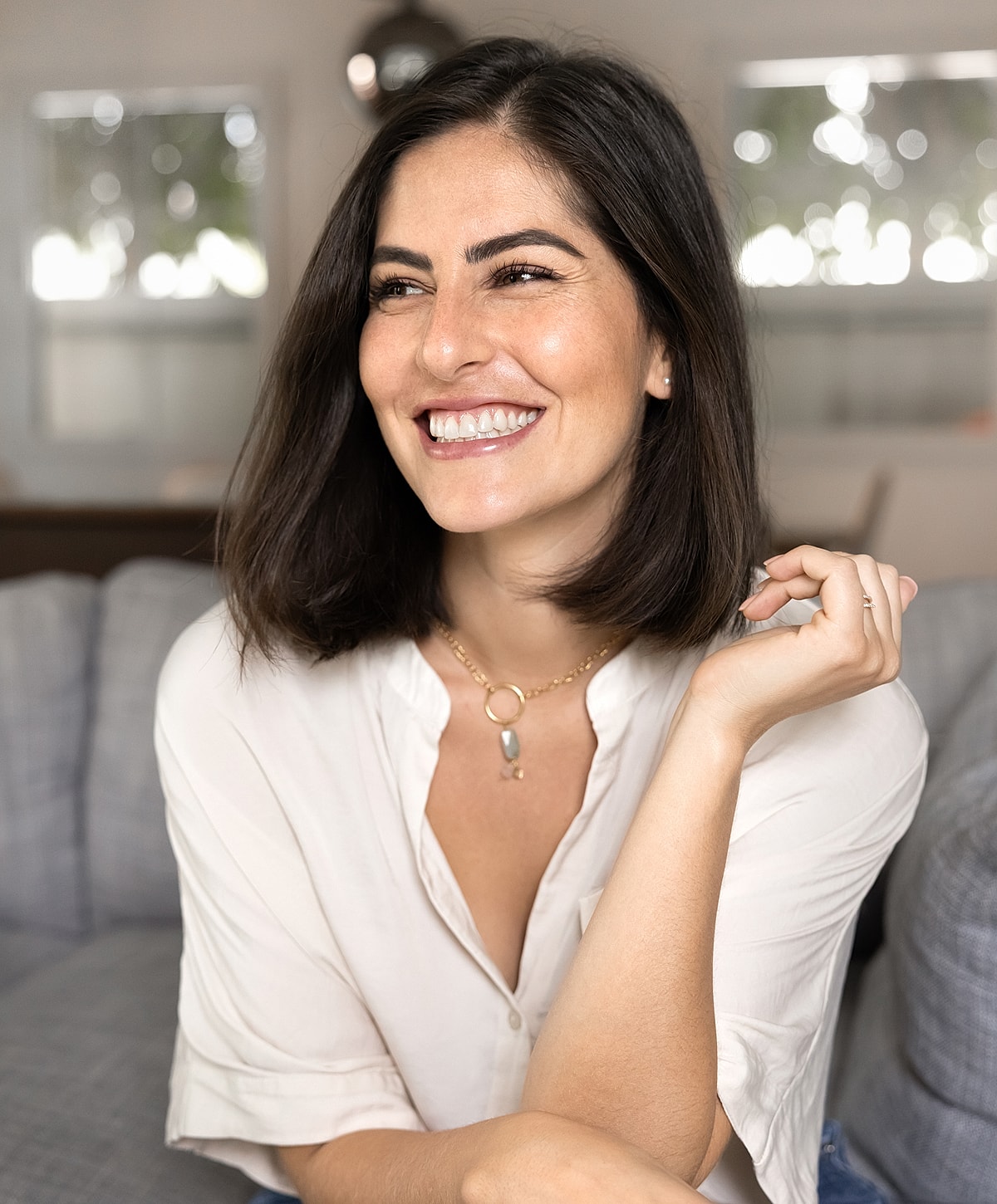 Smiling woman wearing a necklace indoors.