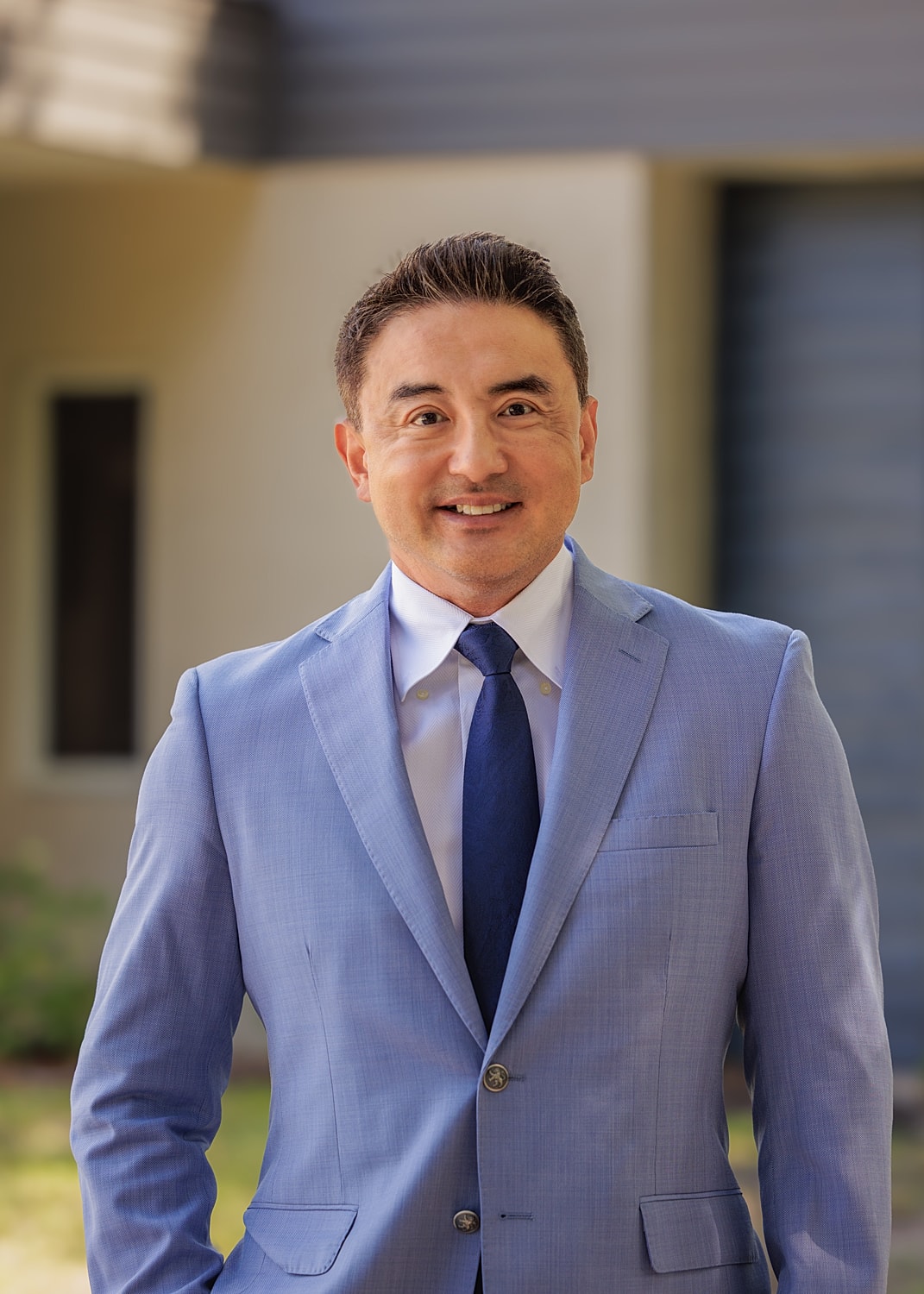Smiling man in a blue suit outdoors.
