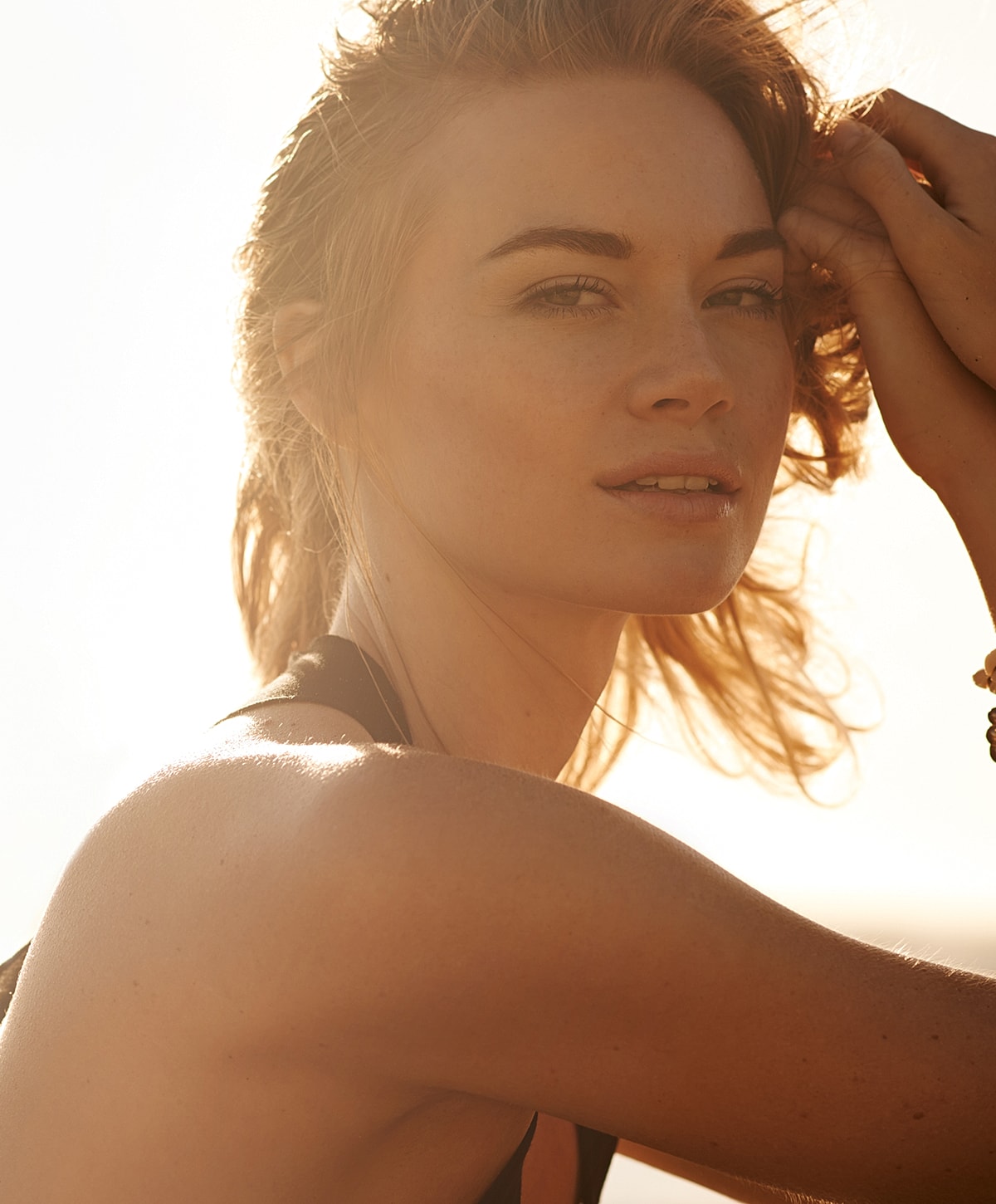 Woman with wavy hair in soft sunlight.