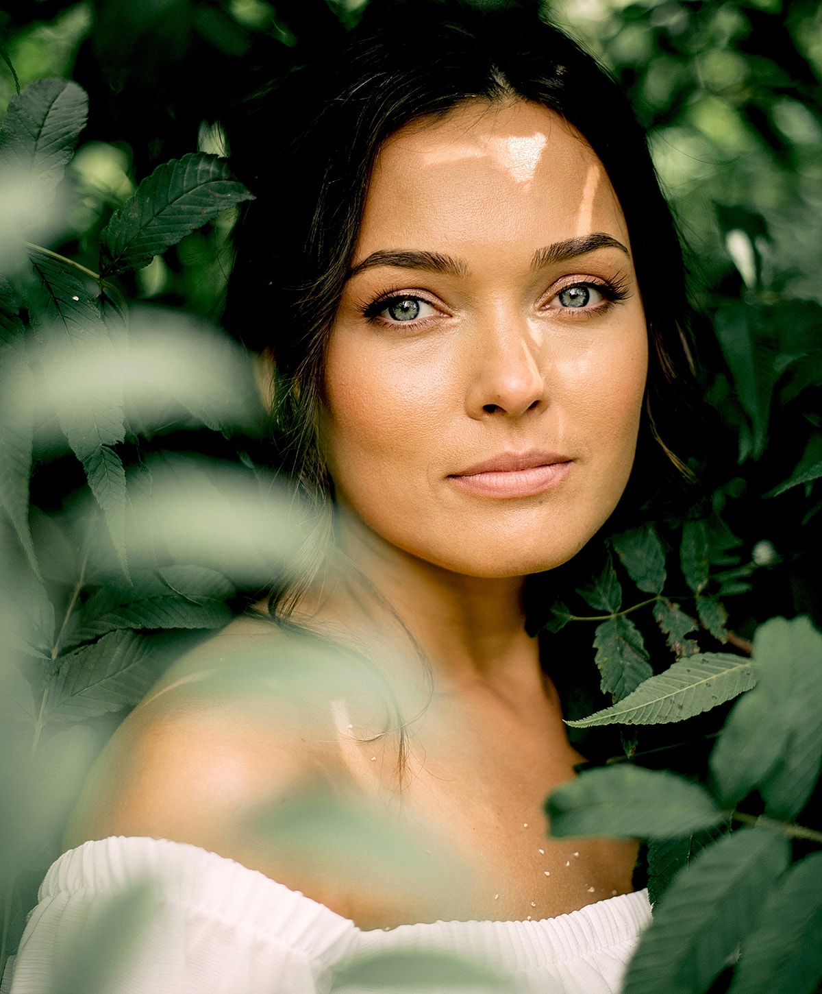 Woman with beautiful eyes among green foliage.