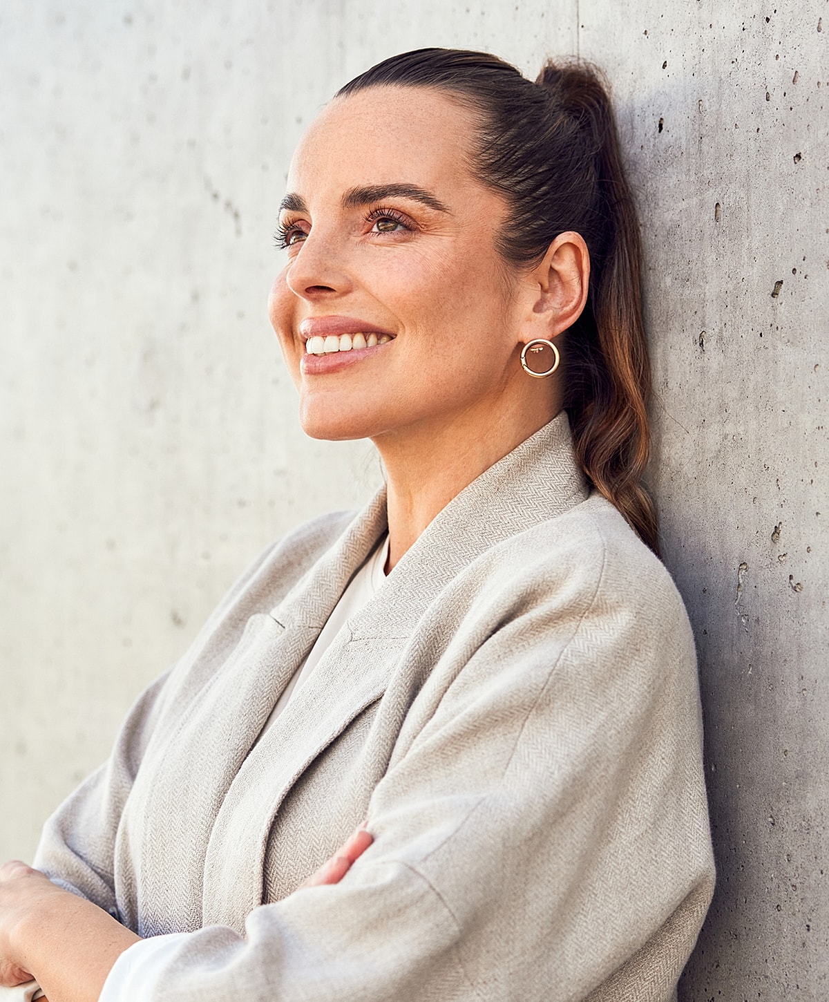 Smiling woman leaning against a concrete wall.