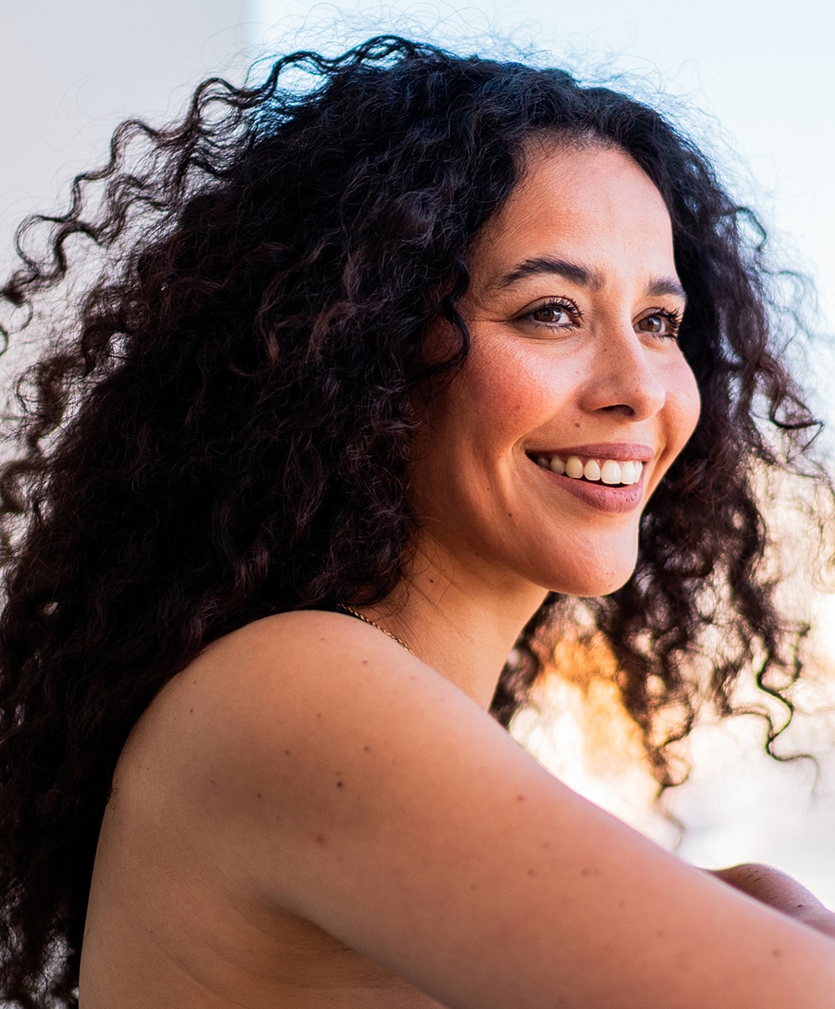 Smiling woman with curly hair outdoors.