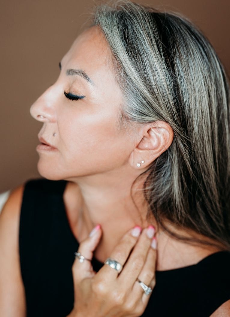 Melbourne facial cosmetic surgery model touching neck with closed eyes, serene expression.