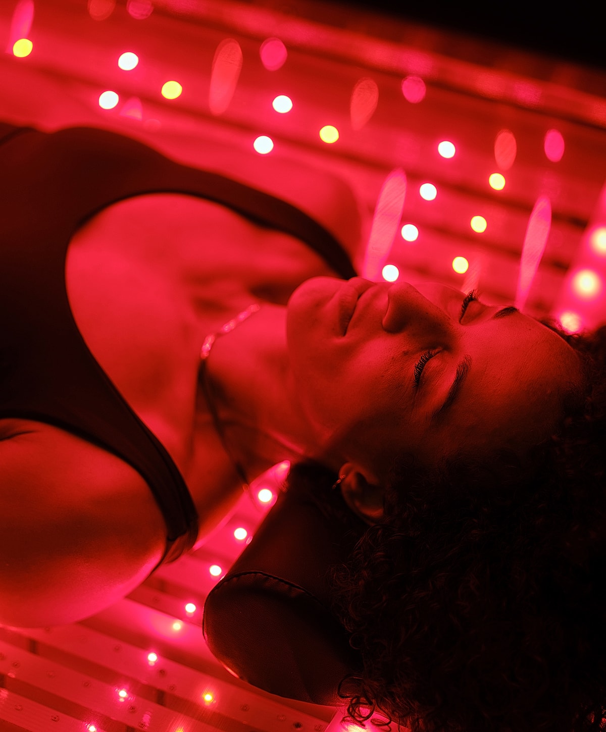 Melbourne red light therapy model relaxing under red LED lights.