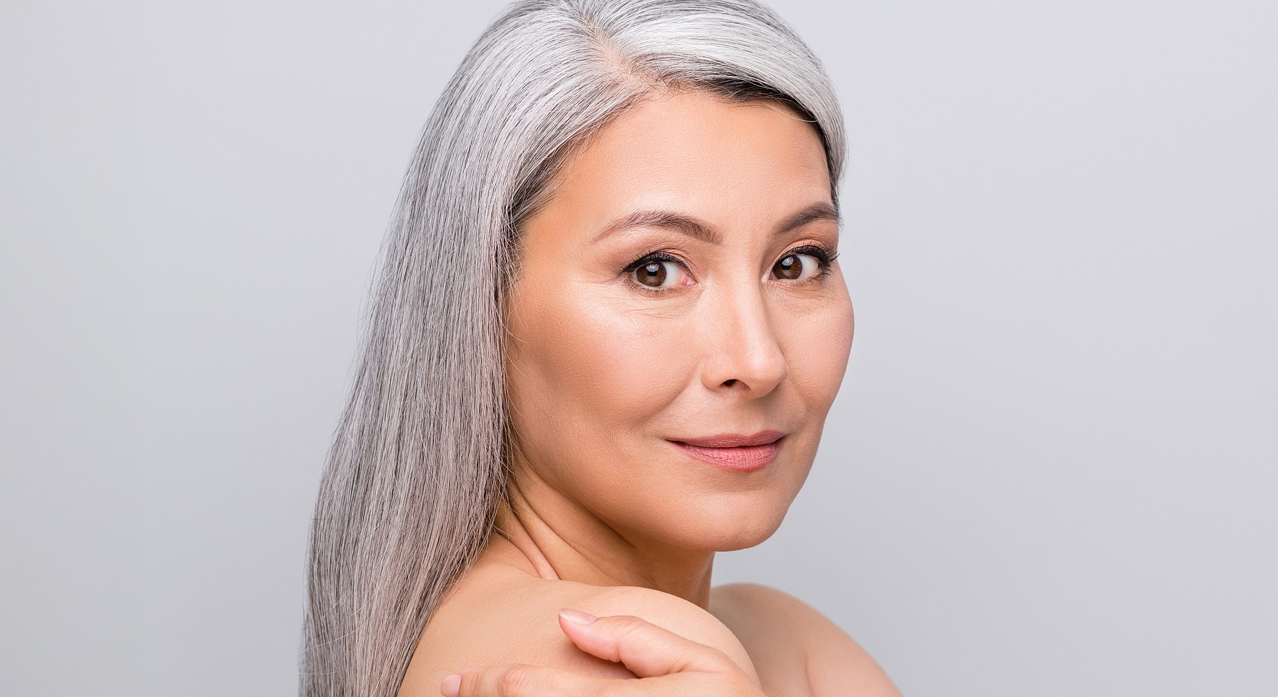 Woman with long gray hair smiling softly.