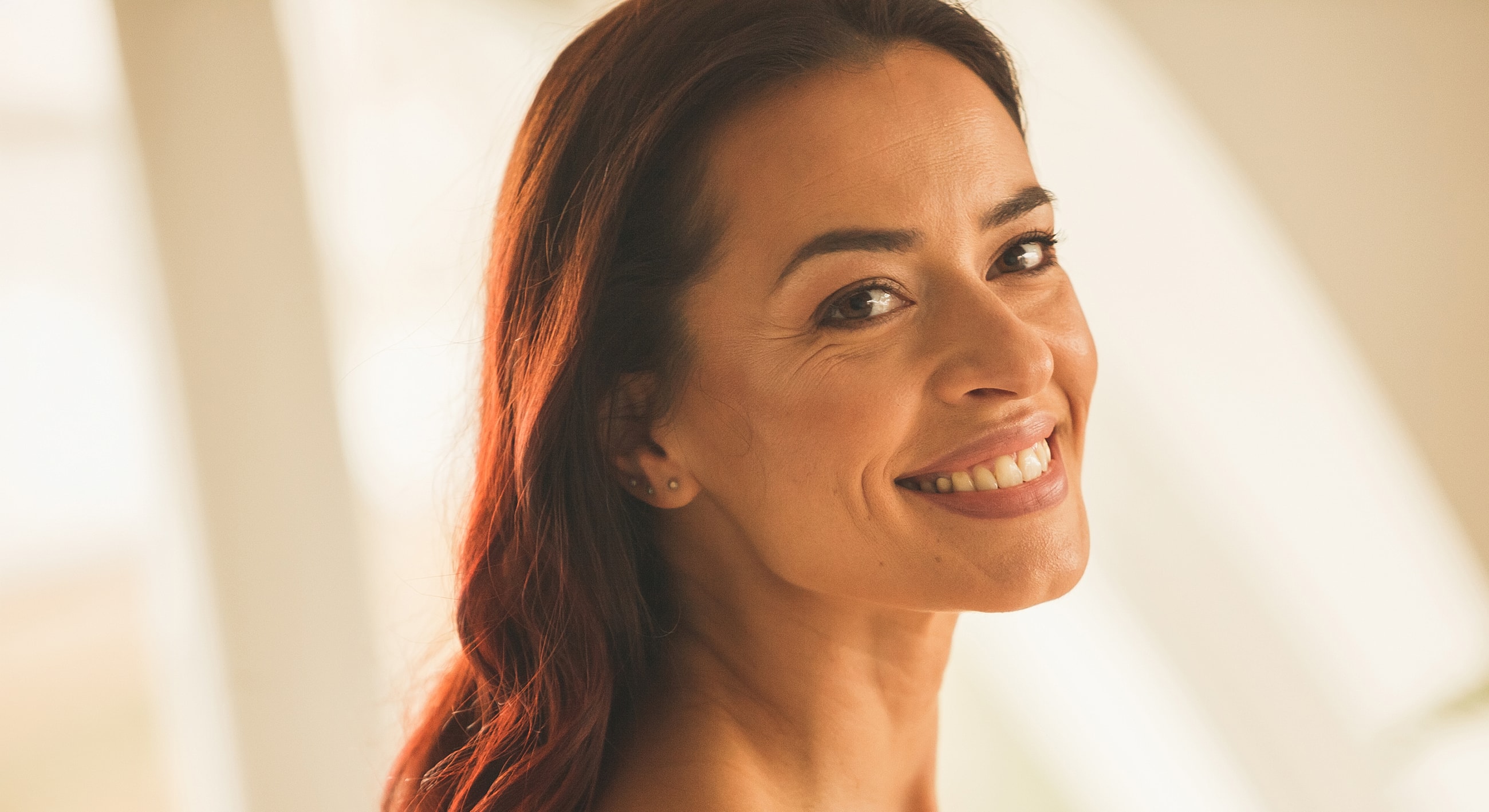 Smiling woman with long, dark hair indoors.